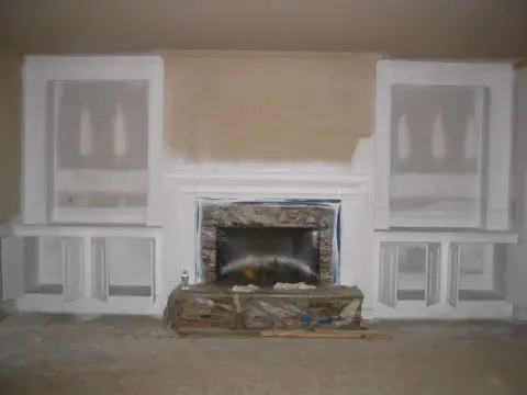 A fireplace in the middle of a room with white walls.