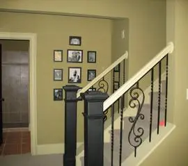 A staircase with black and white railing, some pictures on the wall.