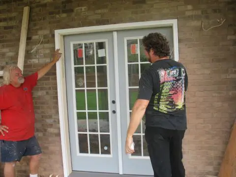 Two men are standing in front of a door.