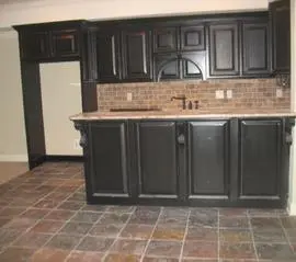 A kitchen with black cabinets and tile floor.