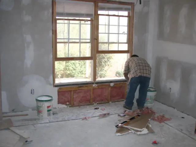 A man is working on the walls of his home.