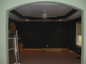A room with a ceiling fan and a black wall.
