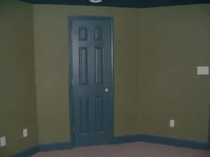 A room with green walls and dark blue door.