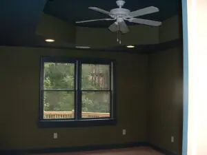 A room with a ceiling fan and windows.