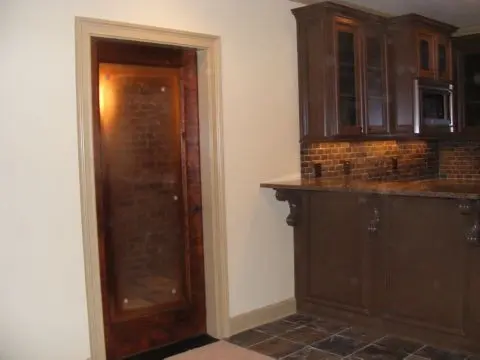 A bathroom with a wooden door and brown cabinets.