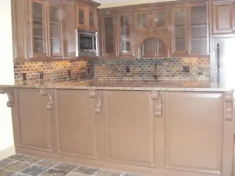 A kitchen with brown cabinets and tile backsplash.