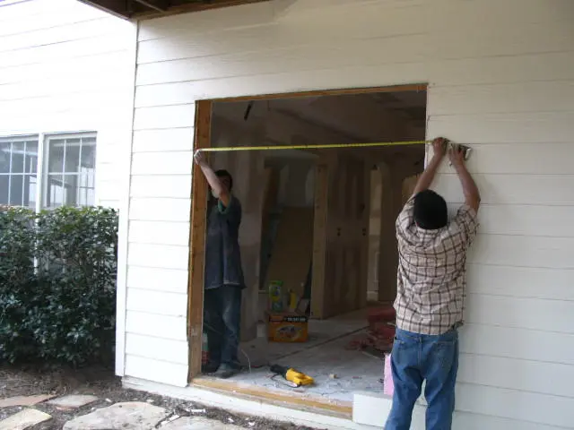 Two men are working on a house.