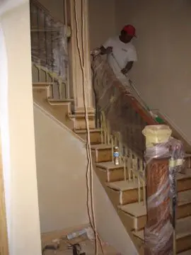 A man painting the bottom of stairs with paint.