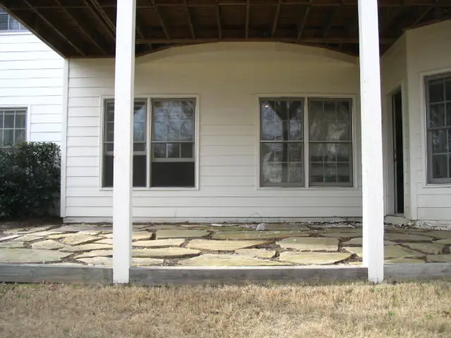 A porch with a stone floor and white walls.