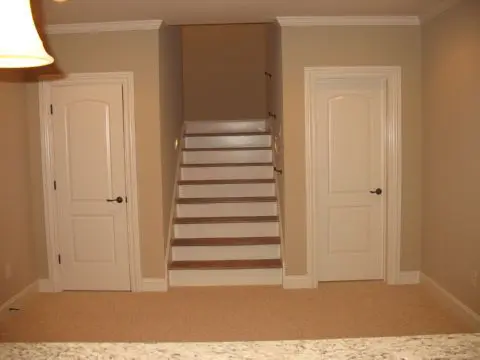 A room with two doors and stairs leading to the second floor.