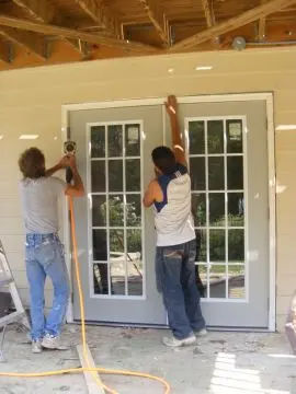 Two men are working on a door.