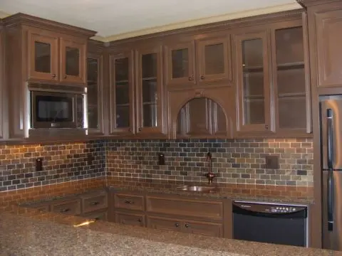 A kitchen with brown cabinets and black counter tops.