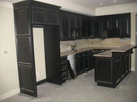 A kitchen with black cabinets and white walls.