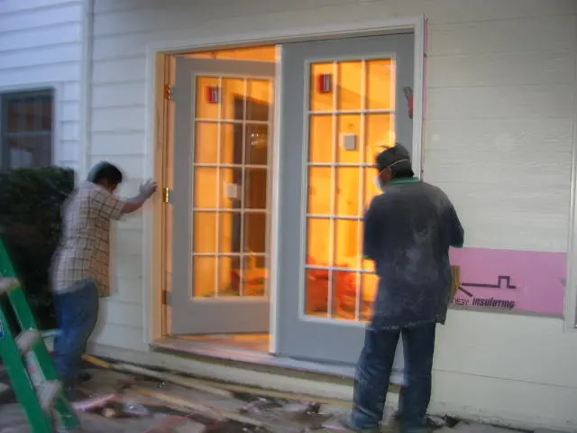 Two men are working on a door.