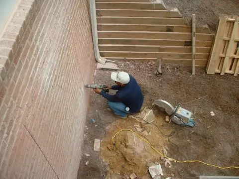 A person in construction gear working on the wall of a building.