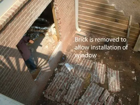 A person is removing the brick from their window.
