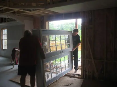 Two people are moving a window frame into the house.