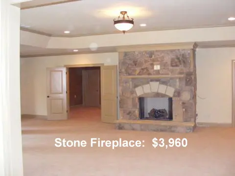 A room with a stone fireplace and carpet.