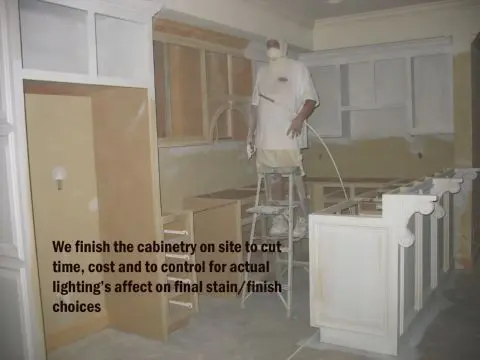A man in white shirt painting cabinets with words.