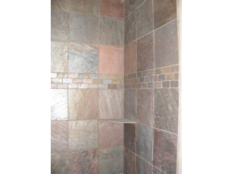 A tiled shower with the door open.