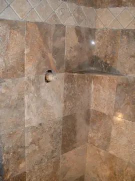 A bathroom with marble tile and a shower head.
