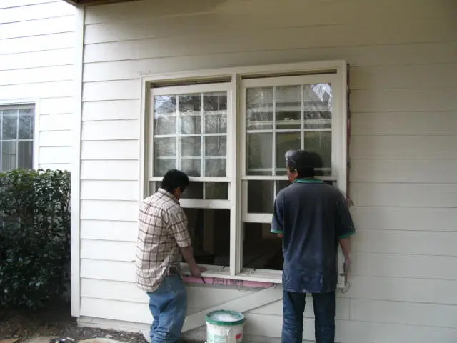 Two men are painting the windows of a house.