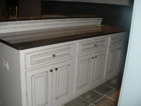 A kitchen with white cabinets and wooden counter tops.