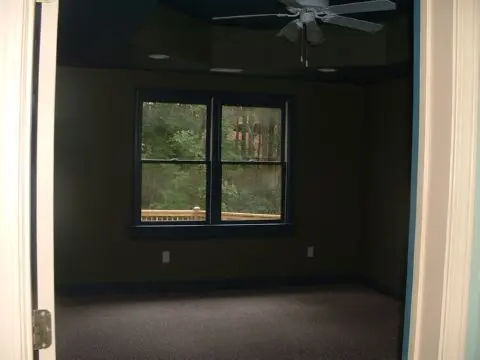 A room with two windows and a ceiling fan.