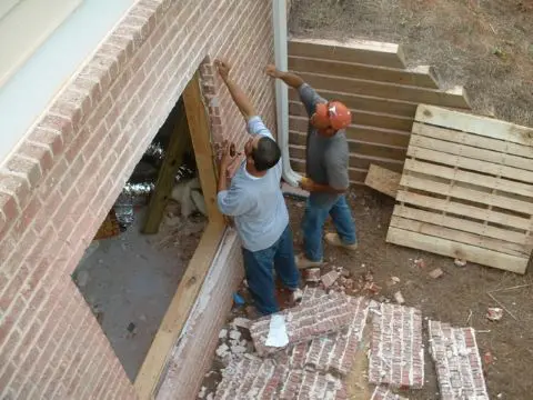 Two men working on a brick wall.