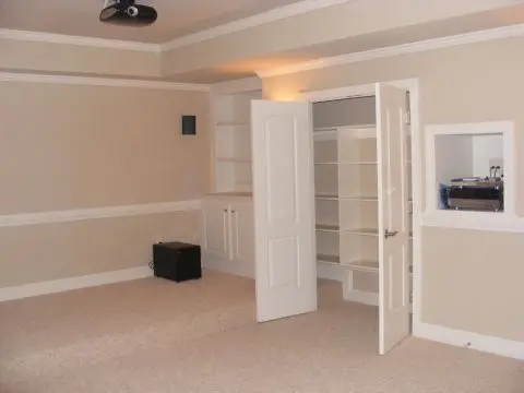 A room with two doors open and shelves in it.