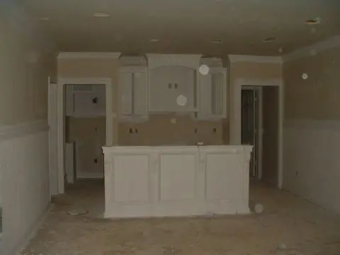 A kitchen with white cabinets and walls in the middle of it.