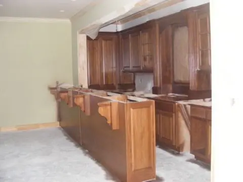 A kitchen with wooden cabinets and marble counter tops.