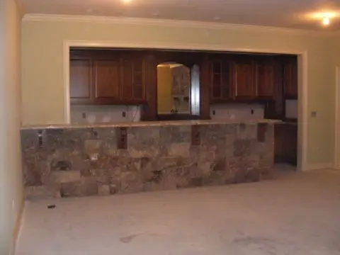 A kitchen with stone walls and wood cabinets.