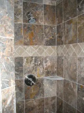 A tiled shower with a marble tile floor.