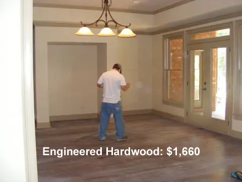 A man standing in an unfinished room with wood floors.