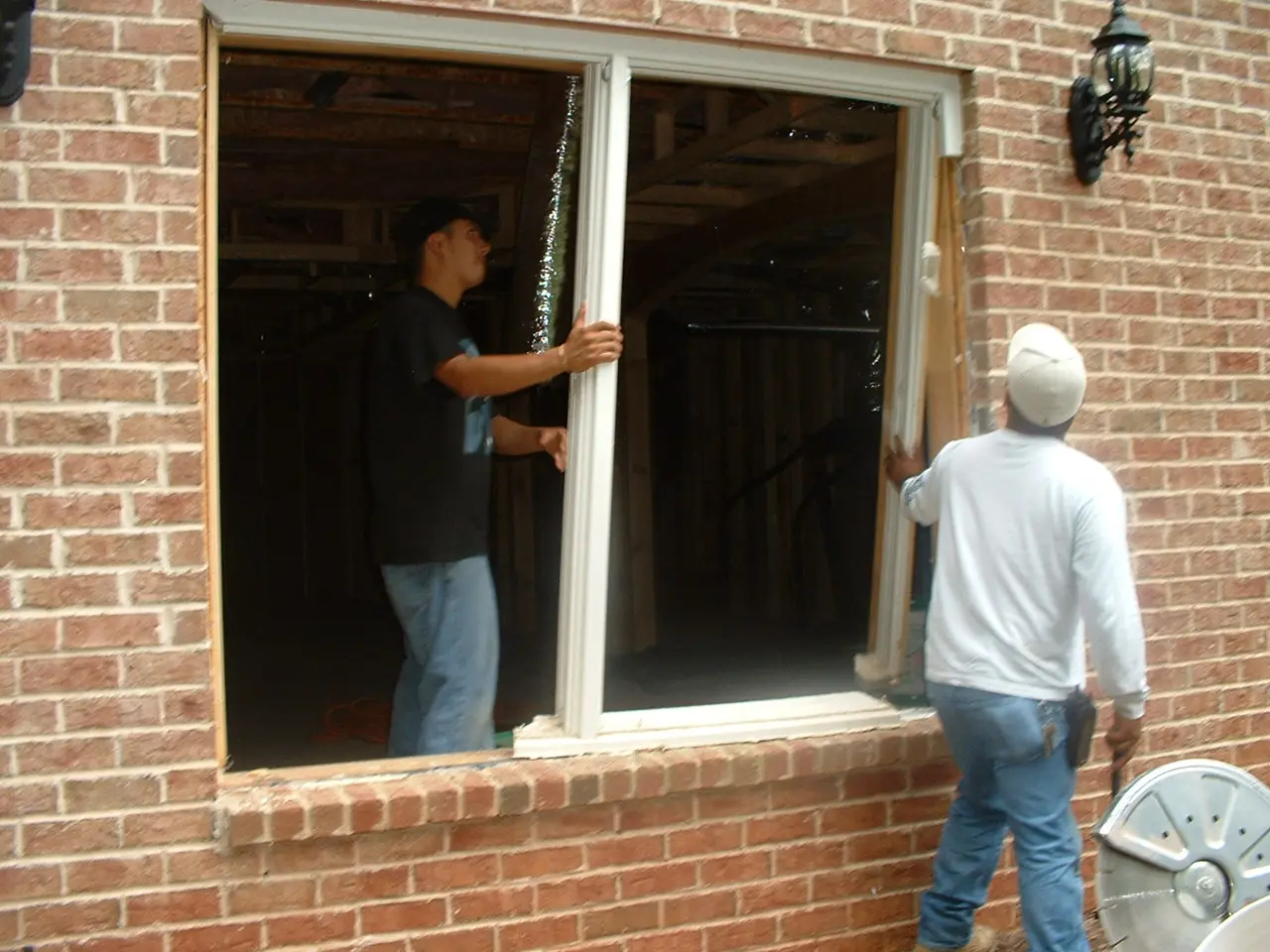 Two men are working on a window.