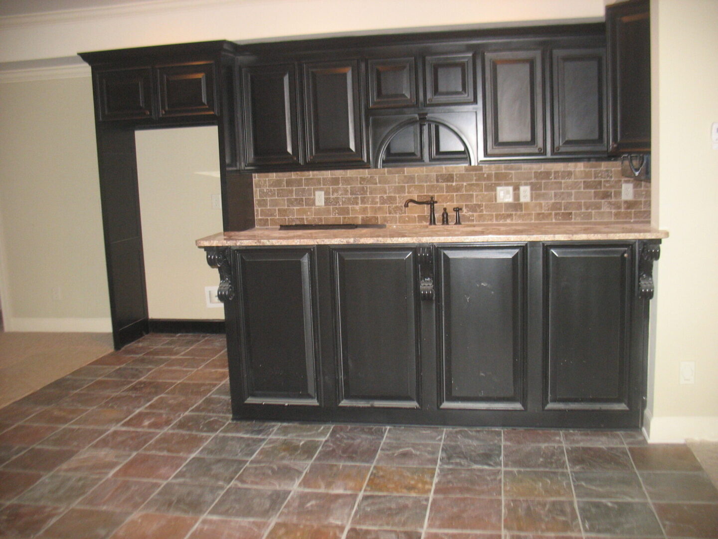 A kitchen with black cabinets and tile floor.
