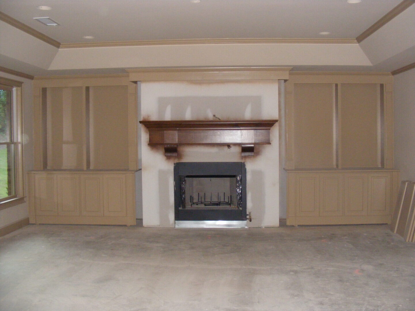 A fireplace in the middle of a room with wooden cabinets.