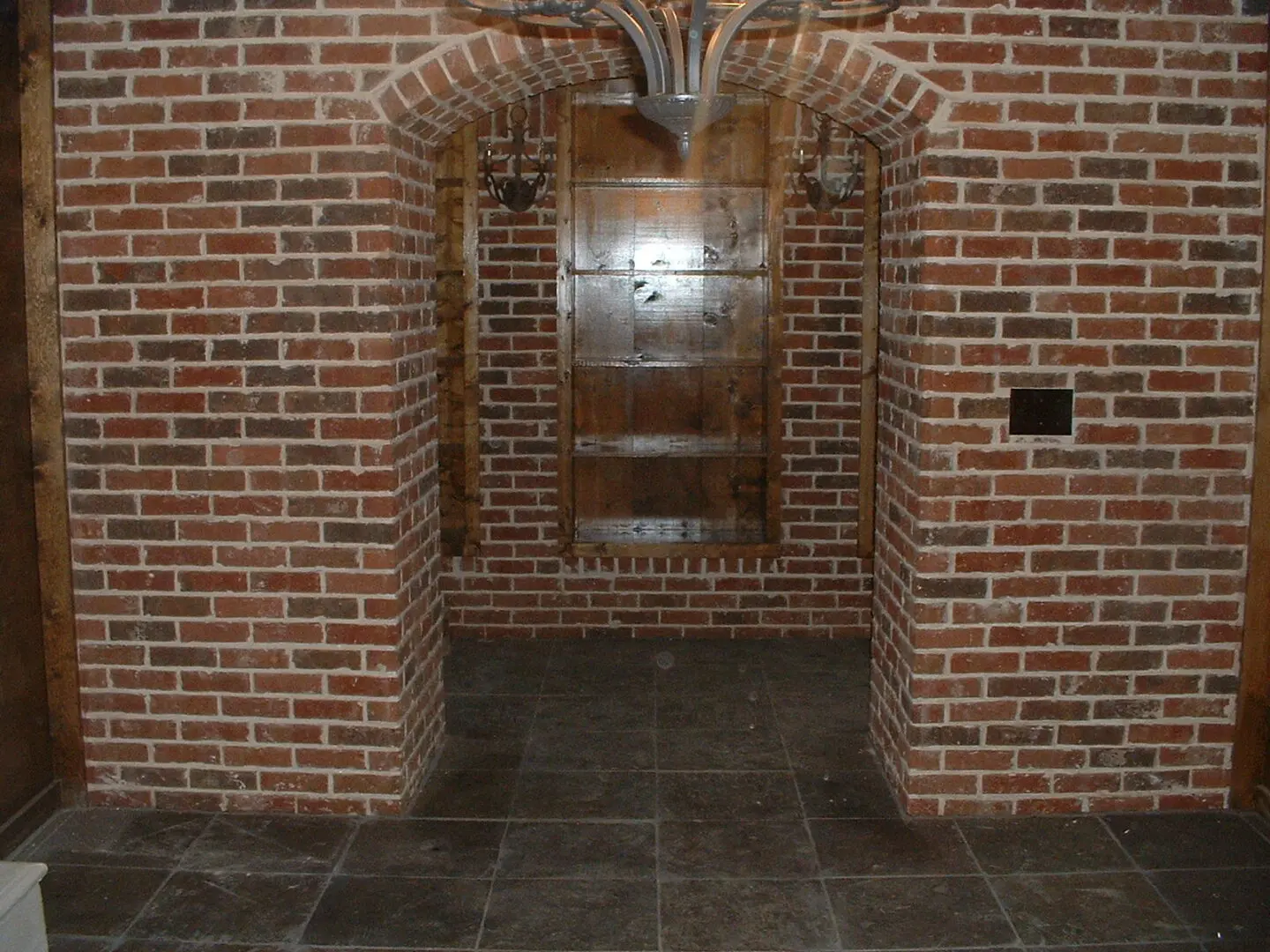 A brick wall with two arches and a door.