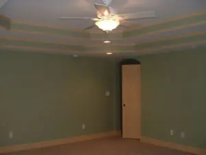 A room with green walls and ceiling fan.
